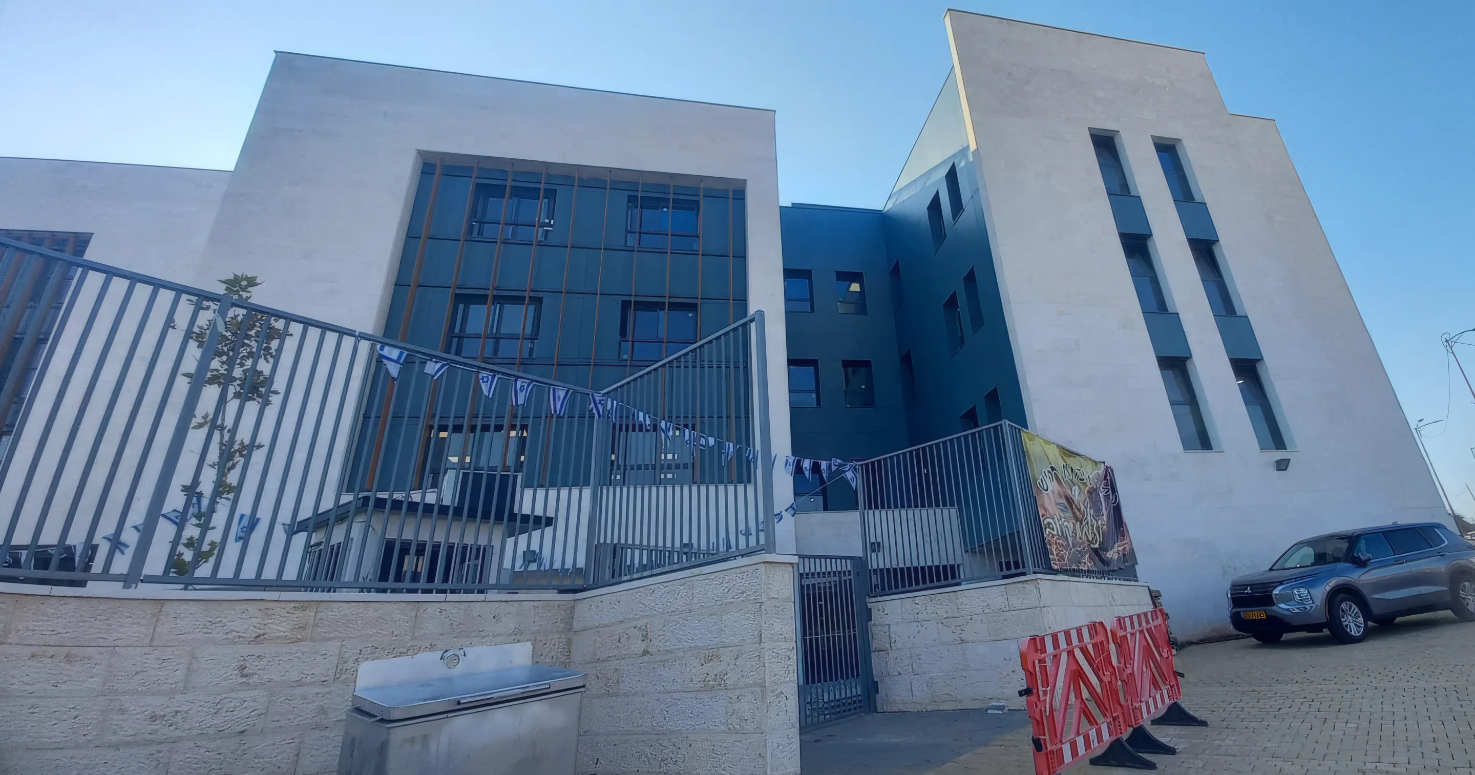 בניין ישיבת זיו אור חריש מבחוץ, עם גדר מרפסת ושמיים כחולים