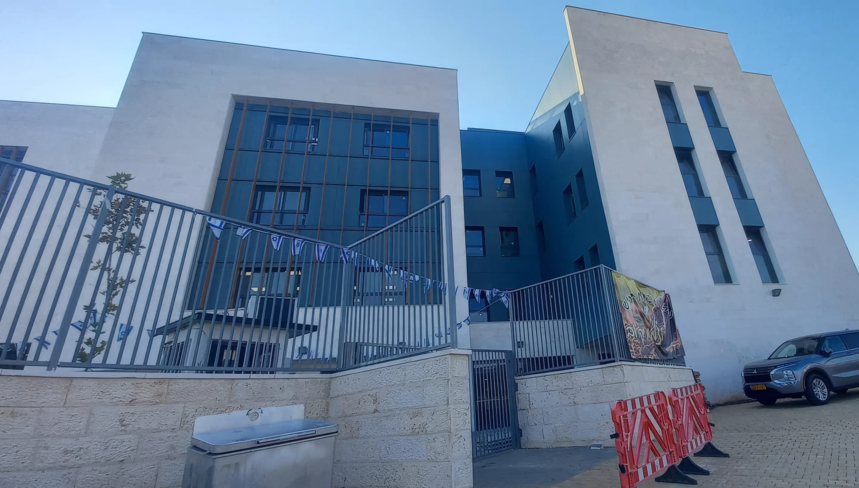 בניין ישיבת זיו אור חריש מבחוץ, עם גדר מרפסת ושמיים כחולים