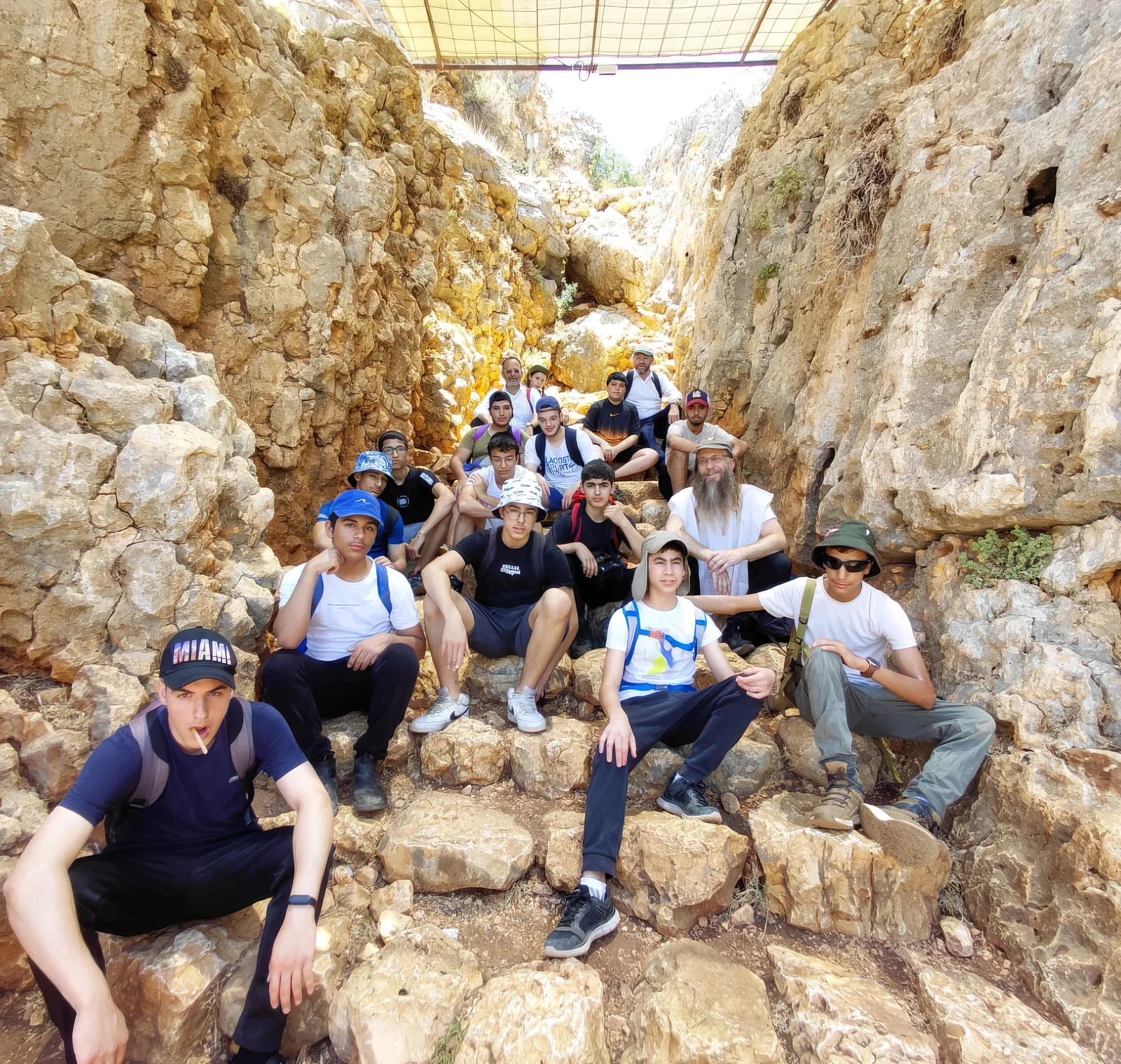 תלמידים וצוות יושבים על סלעים בטיול בנחל
