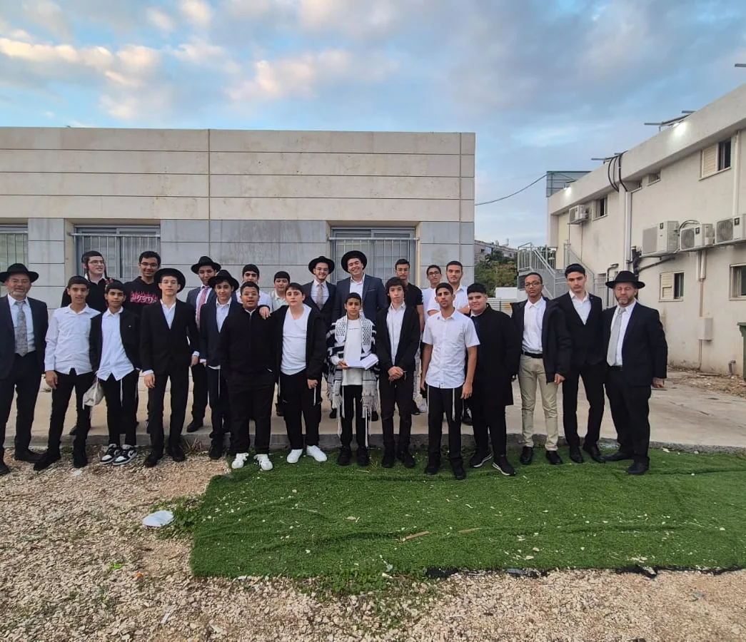 תלמידים ואנשי צוות מצטלמים יחד מול בניין הישיבה בחריש