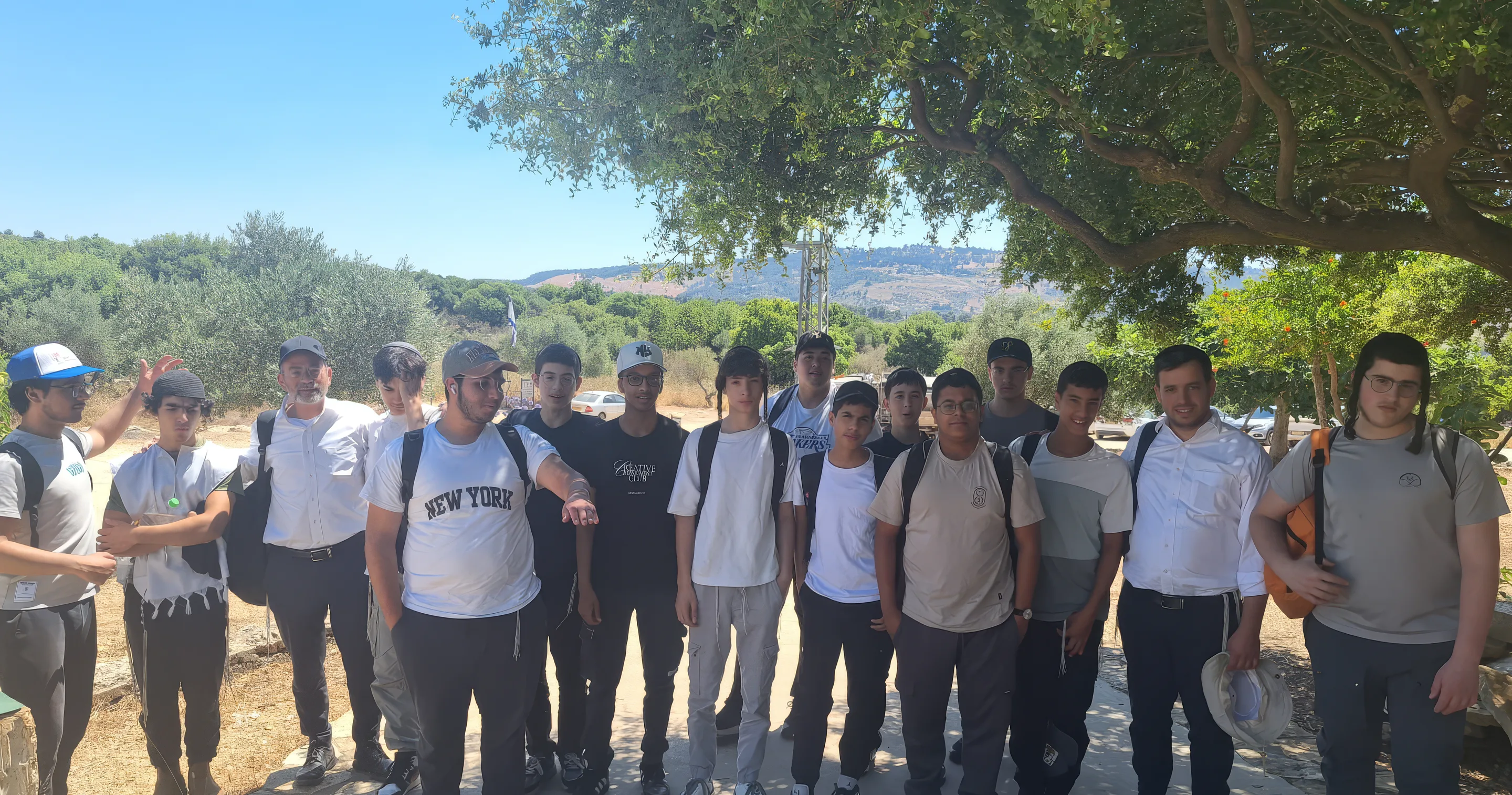 קבוצת תלמידים וצוות בטיול הקיץ השנתי, בין עצים ונוף הרים