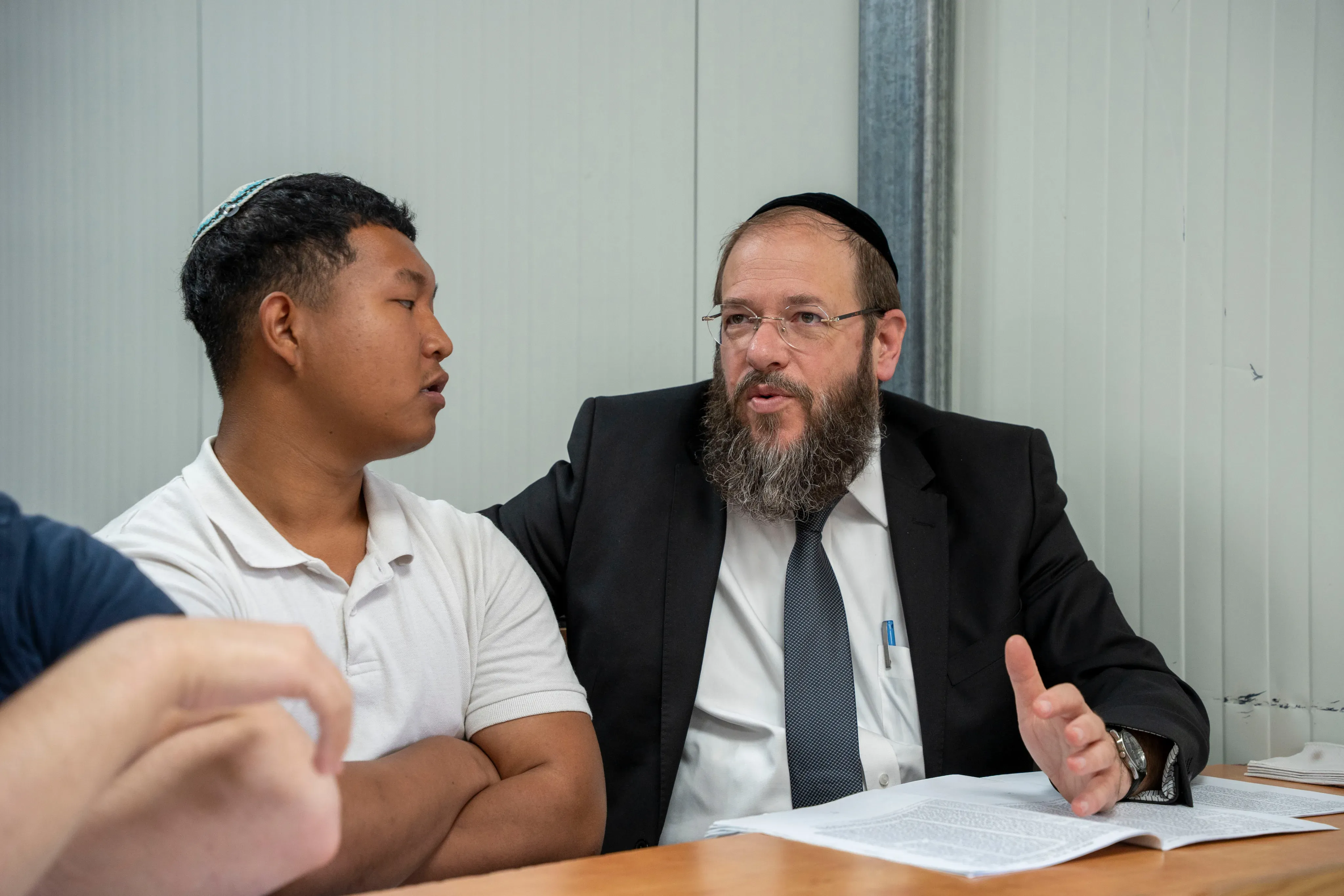 רב בשיחה אישית קרובה עם תלמיד, יושבים זה לצד זה ועיינים במסמך על השולחן