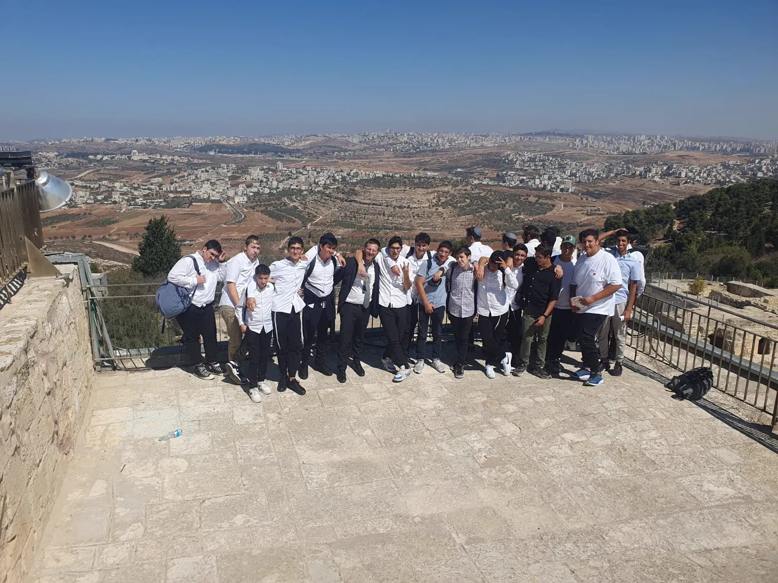 קבוצת תלמידים מצטלמת בטיול על מרפסת תצפית, נוף גבעות ובנייני ירושלים ברקע