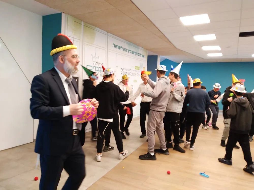 מבוגר בחליפה מחזיק כובע פורים ליד רוקדים - משנכנס אדר - רוקדים יחד