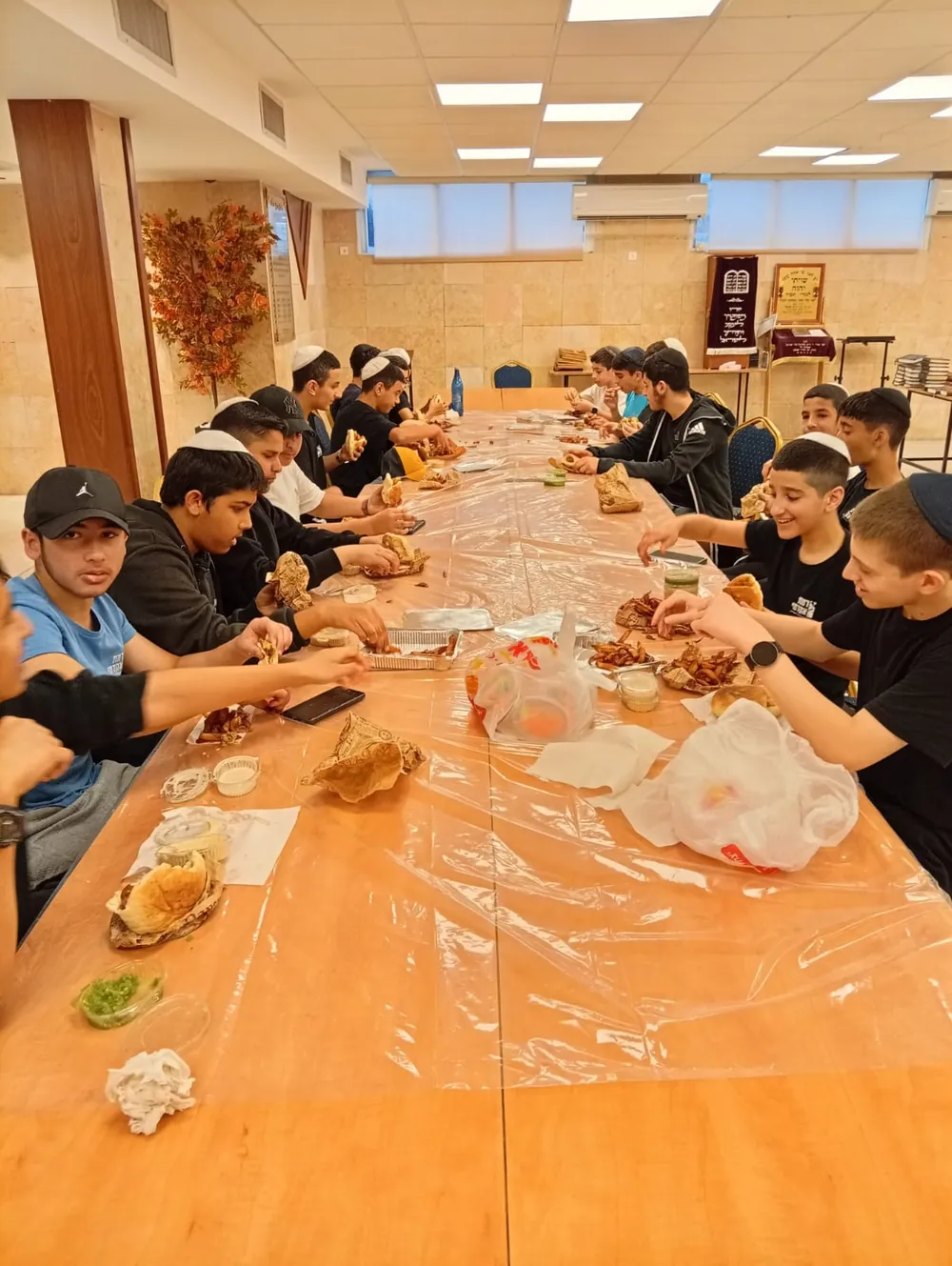 תלמידים אוכלים סביב שולחן ארוך - יום גיבוש בפארק