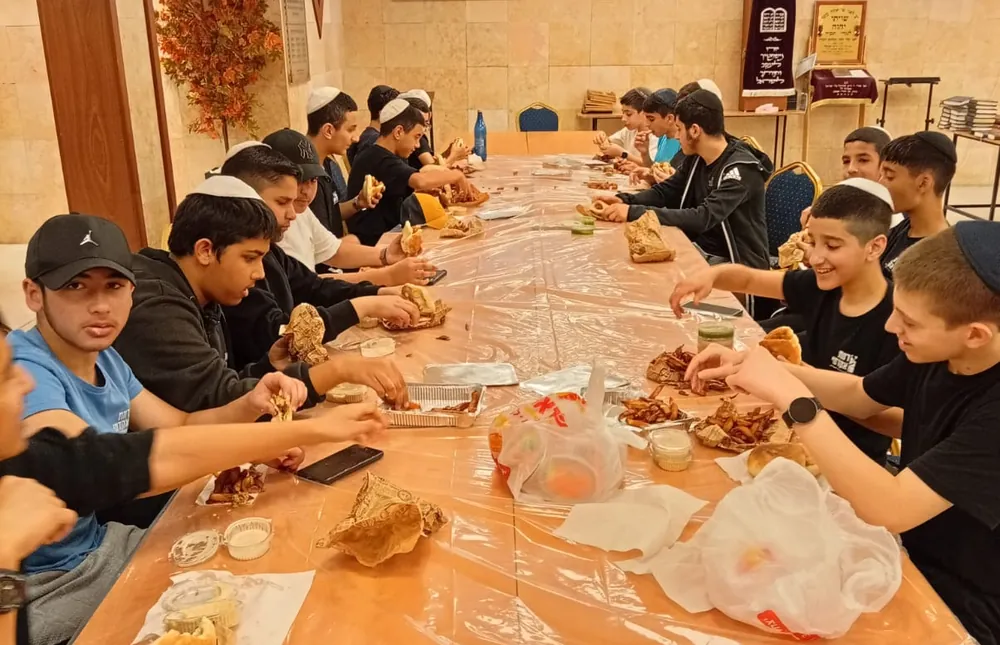 תלמידים אוכלים סביב שולחן ארוך - יום גיבוש בפארק
