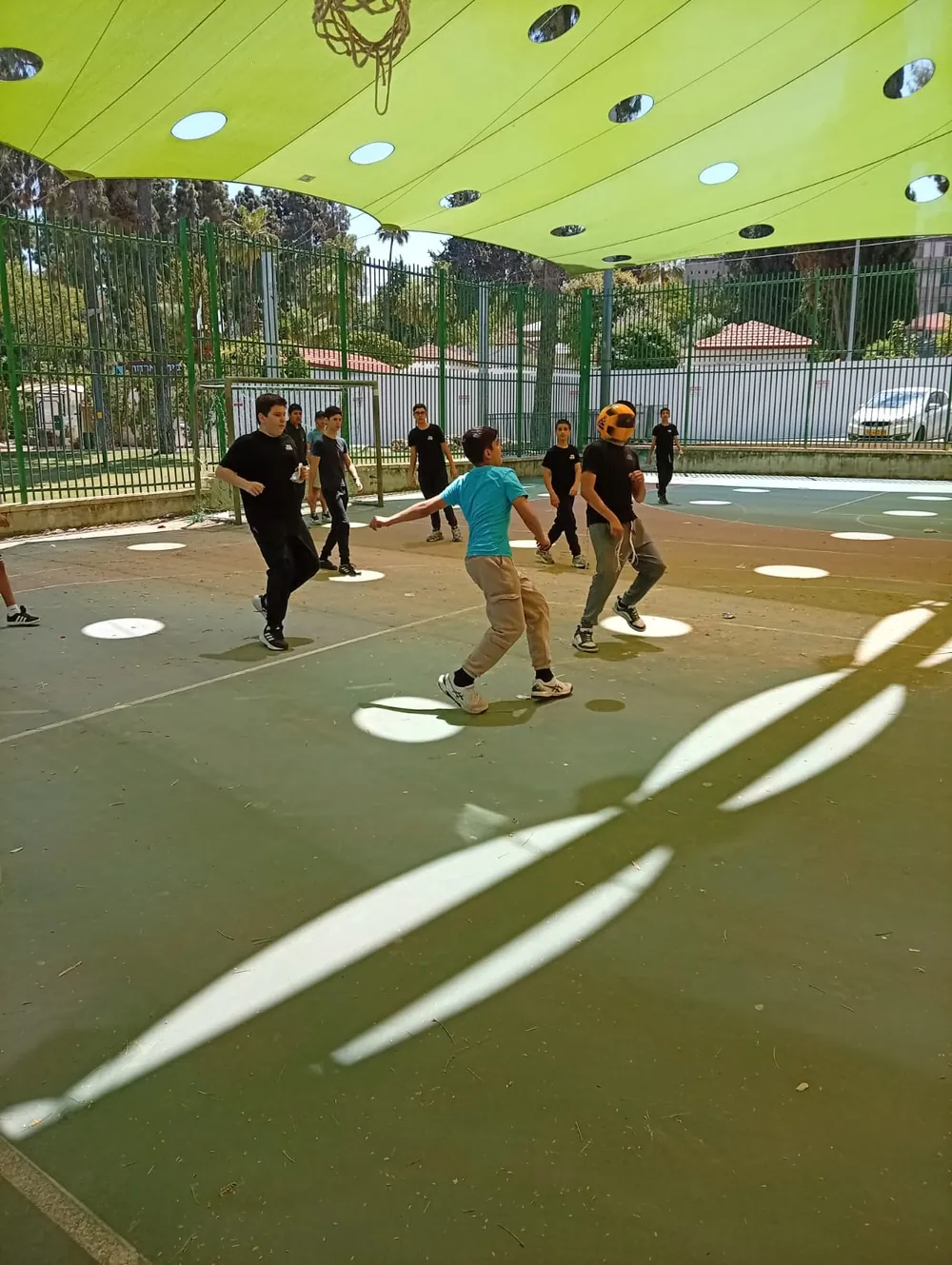תלמידים משחקים בכדור במגרש מקורה - יום גיבוש בפארק