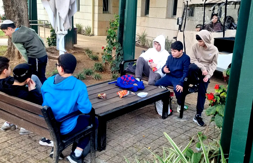 תלמידים יושבים סביב שולחן בחצר מכון דוידסון - יום של ניסויים במכון דוידסון