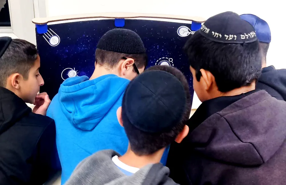 תלמידים סביב תיבת פעילות מעוצבת כחלל - יום של ניסויים במכון דוידסון