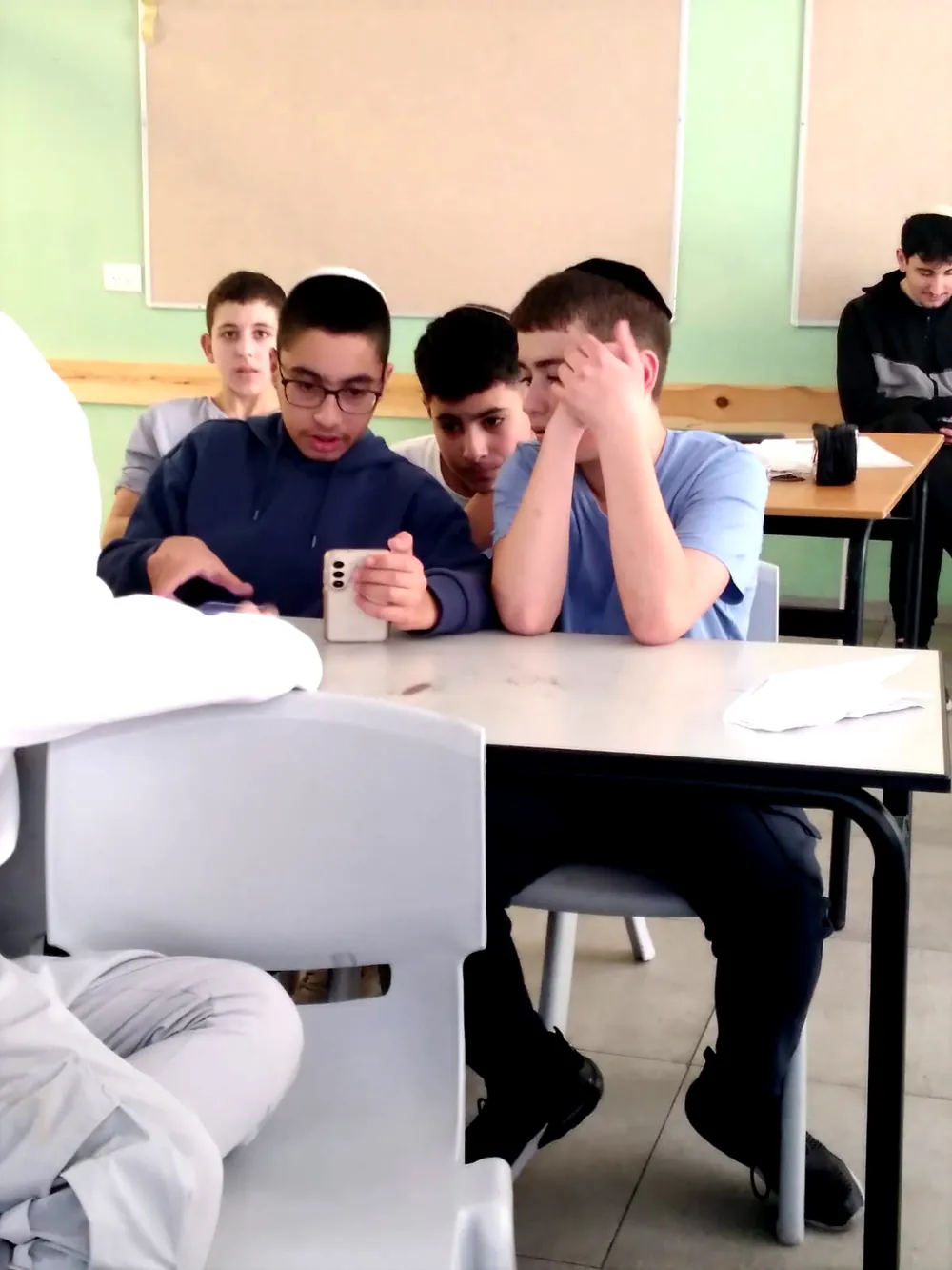 תלמידים מסתכלים יחד על טלפון בכיתה - יום אנגלית ברמת אקדמי