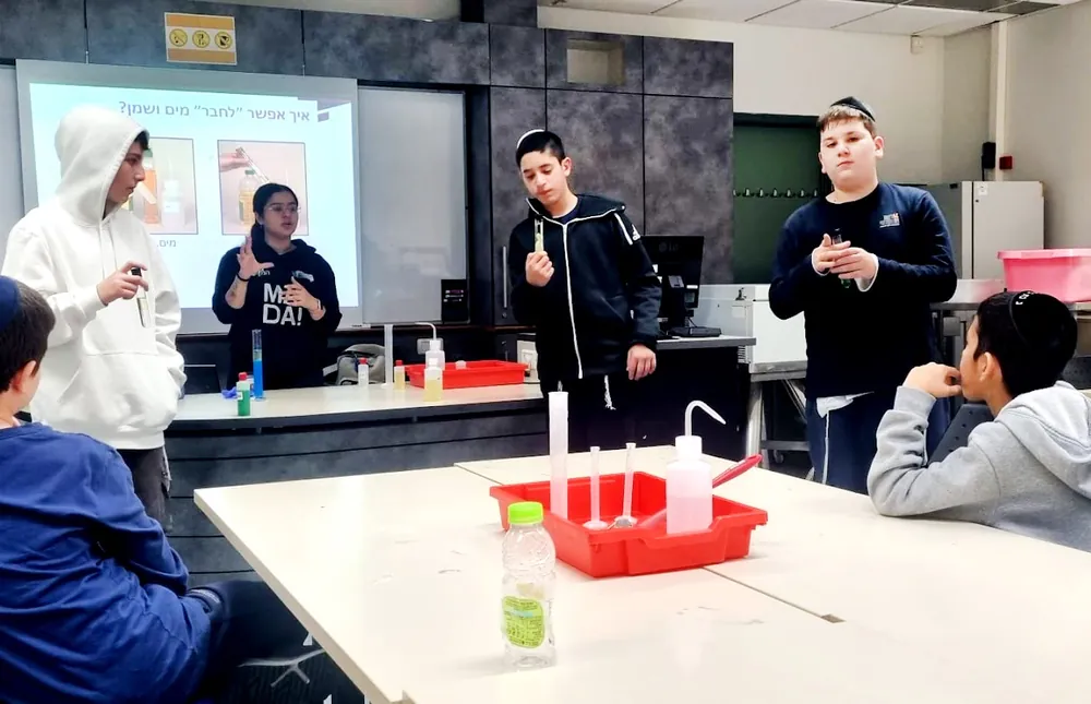 הדגמת ניסוי מול תלמידים עם בקבוקים ומבחנות - רמת אקדמי באר יעקב, מהספר אל המעבדה