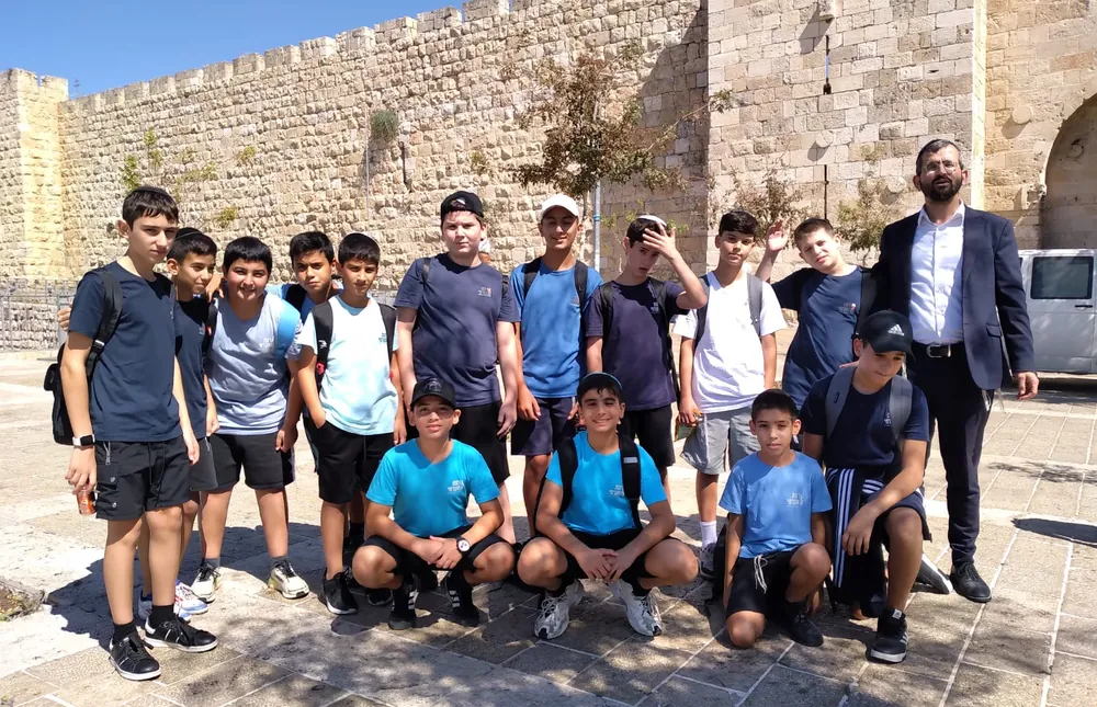 קבוצת תלמידים ומבוגר מול חומת אבן - רמת אקדמי באר יעקב, טיול לירושלים