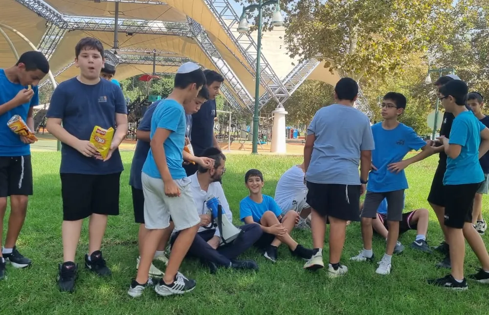 תלמידים ומבוגר מתאספים על הדשא - רמת אקדמי באר יעקב, טיול לירושלים