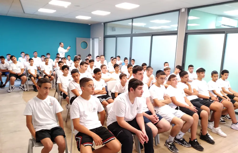 קבוצת תלמידים בחולצות לבנות יושבת באולם - רמת אקדמי באר יעקב, מפגש הורים ותלמידים
