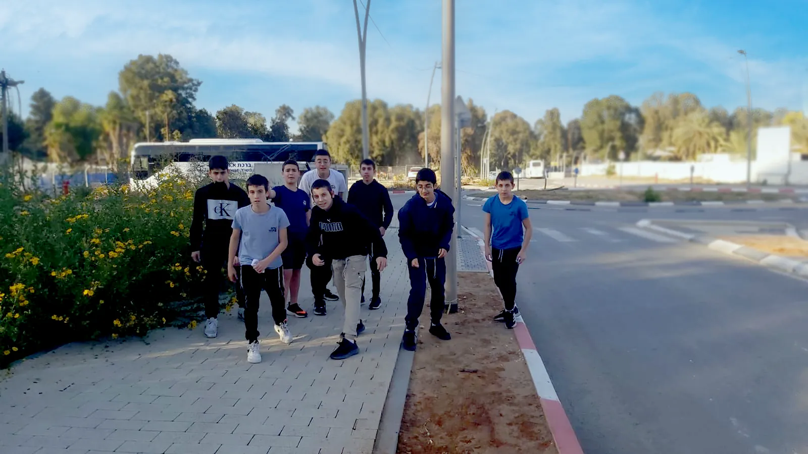 קבוצת תלמידים הולכת על מדרכה ליד כביש - רצים יחד