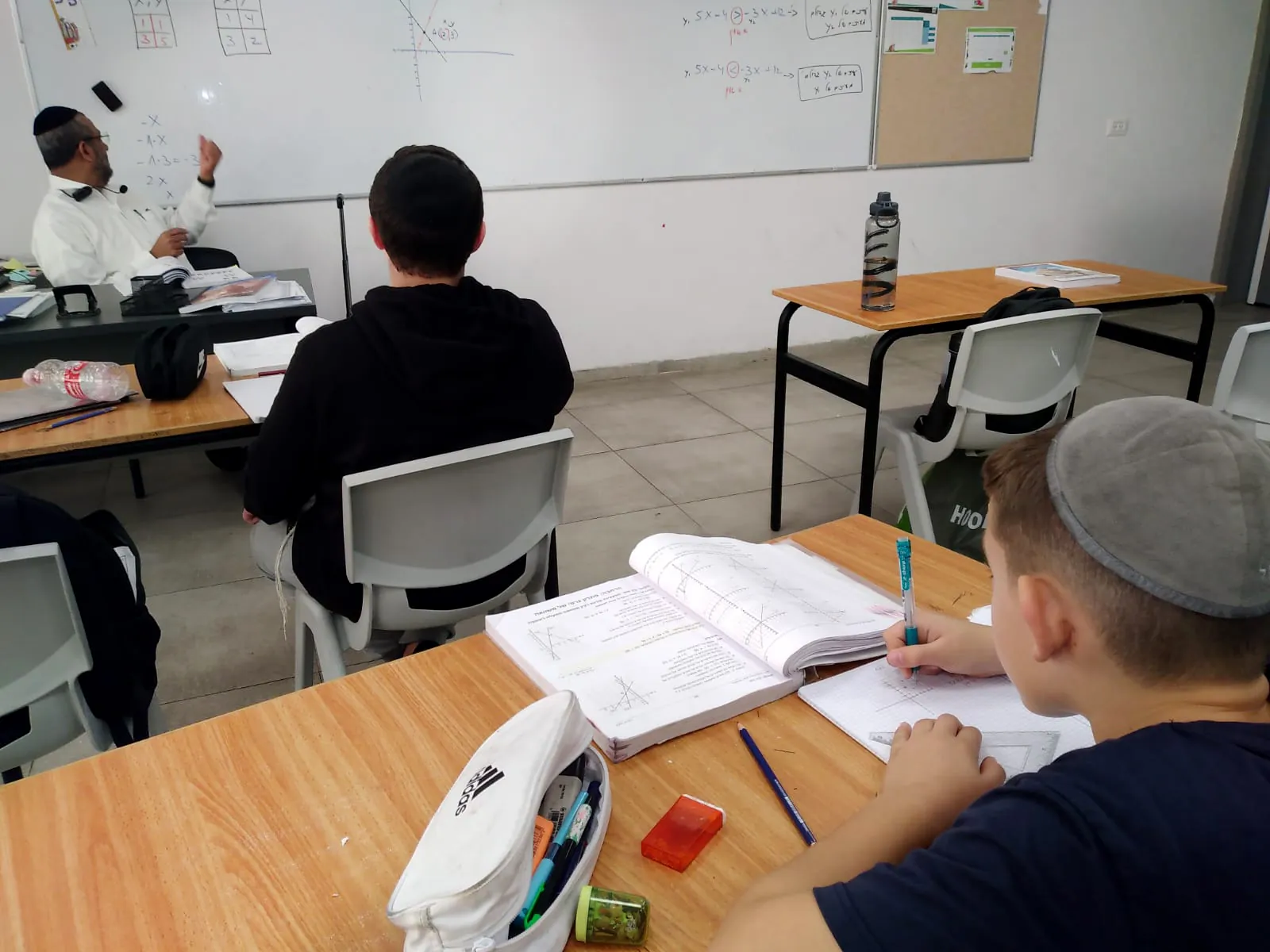 מורה מסביר תרגיל מתמטי מול תלמידים - שיעור מתמטיקה ברמת אקדמי