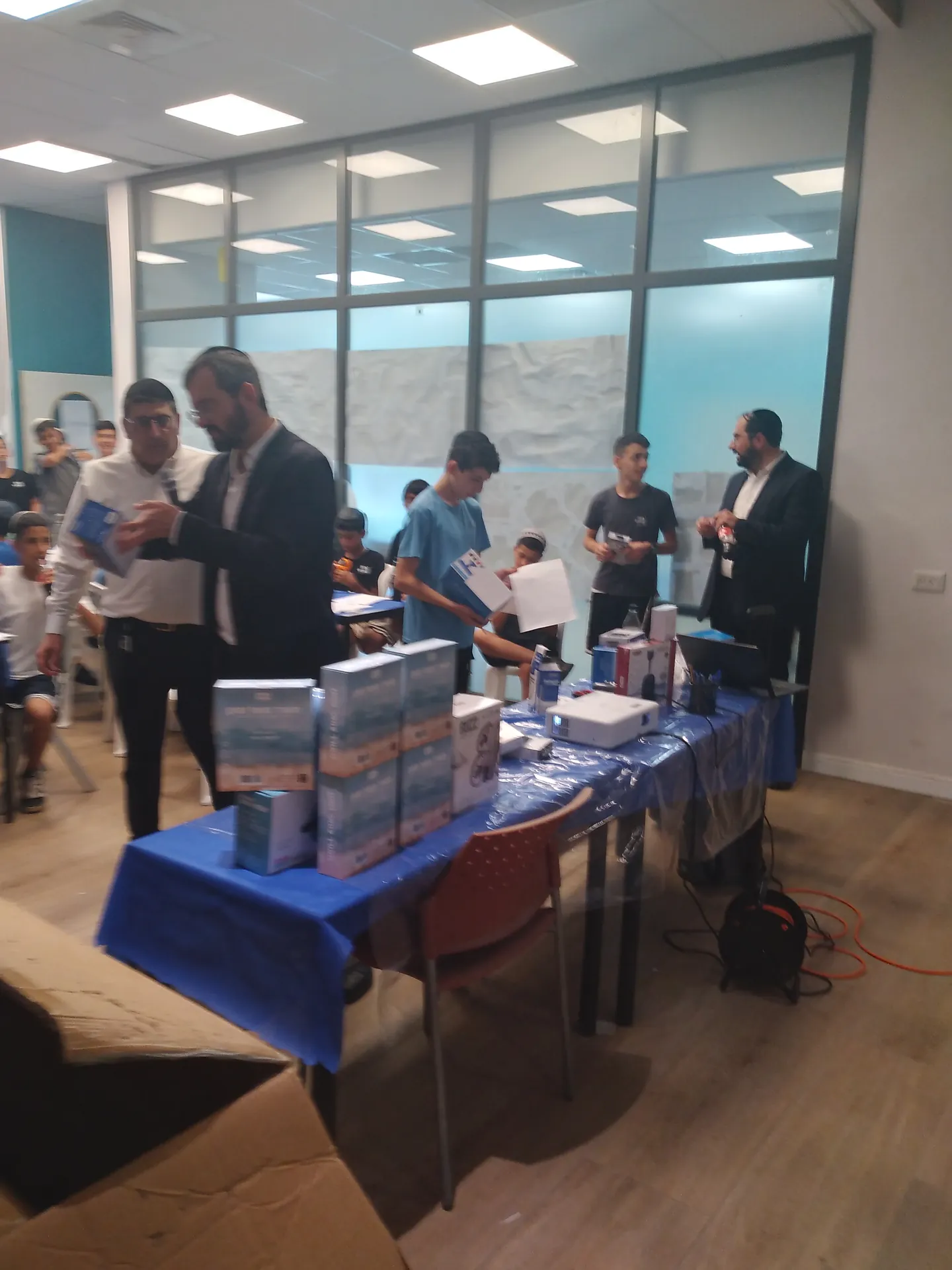 תלמידים מקבלים פרסים ליד שולחן המתנות - סעודת ראש חודש ובינגו עם פרסים