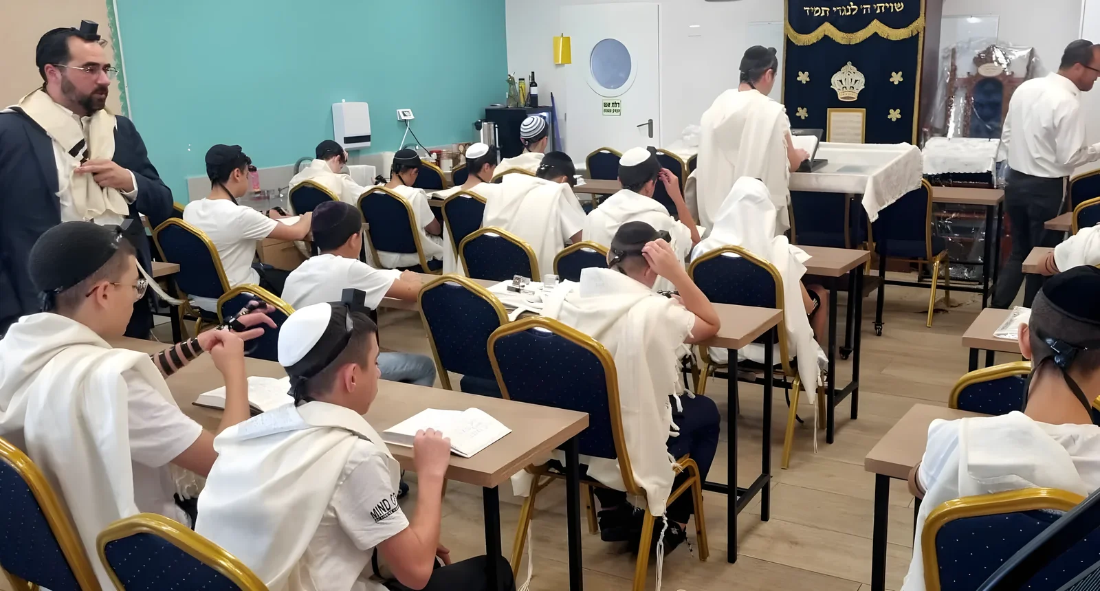 תלמידים מתפללים עם טליתות ותפילין בבית המדרש - ימי תשרי בבית המדרש ובכיתות