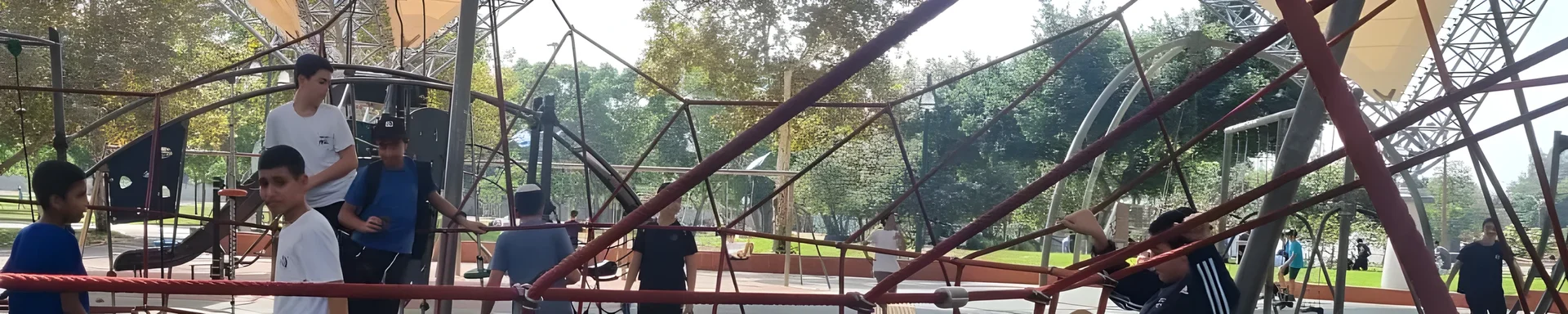 תלמידים משחקים במתקן טיפוס בפארק