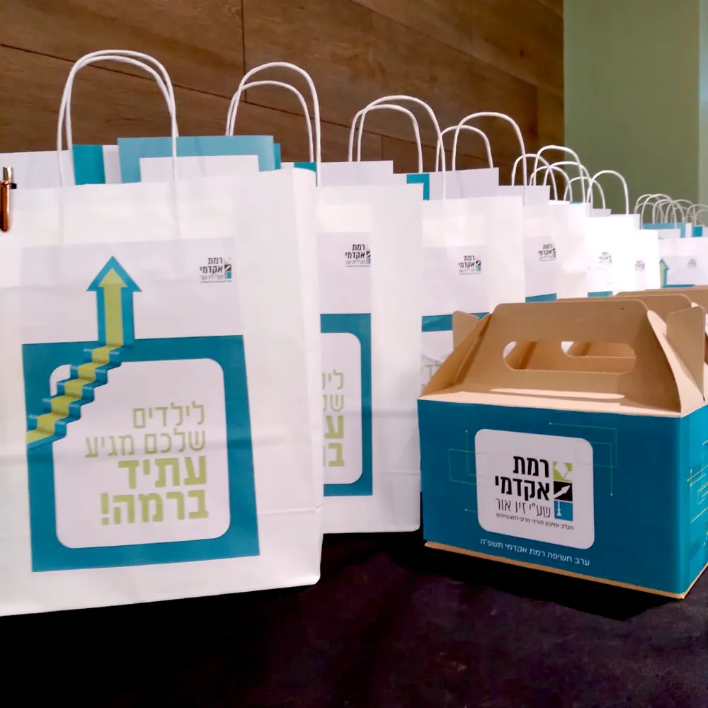 שקיות מתנה וקופסאות ממותגות על שולחן - ערב חשיפה ברמת אקדמי