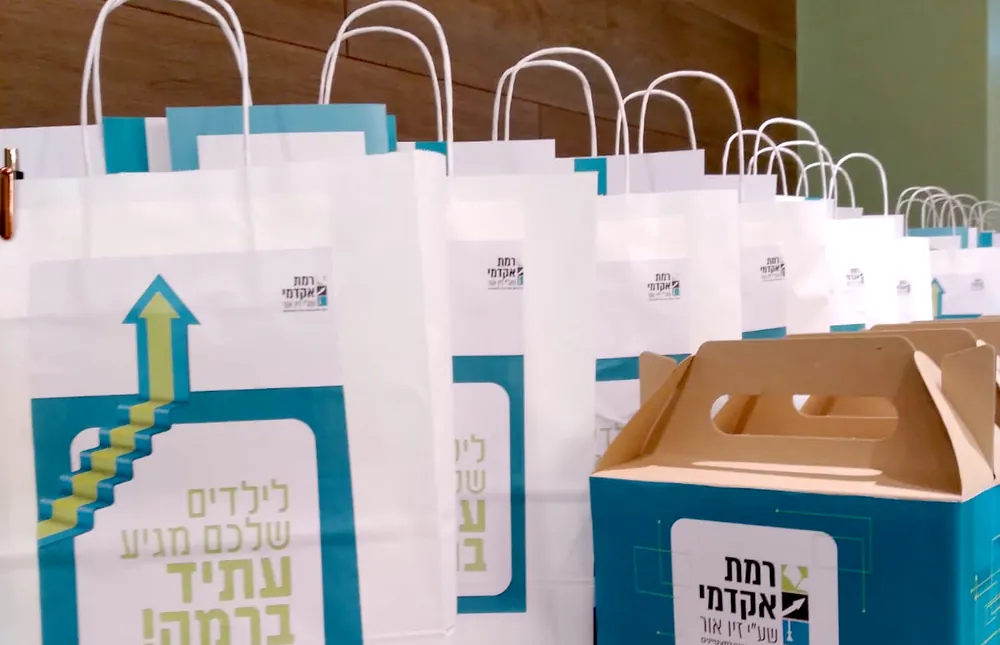 שקיות מתנה וקופסאות ממותגות על שולחן - ערב חשיפה ברמת אקדמי