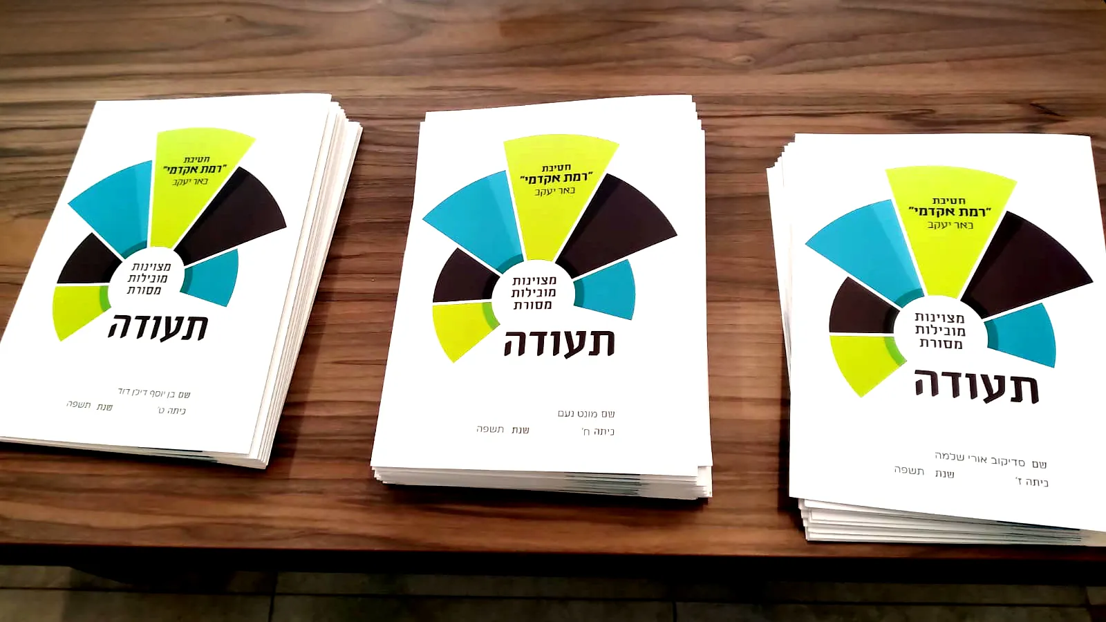 שלוש ערמות של תעודות על שולחן - יום חלוקת התעודות