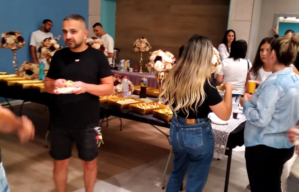 אורחים ליד שולחן כיבוד באולם - תלמידים והורים נפגשו ברמת אקדמי