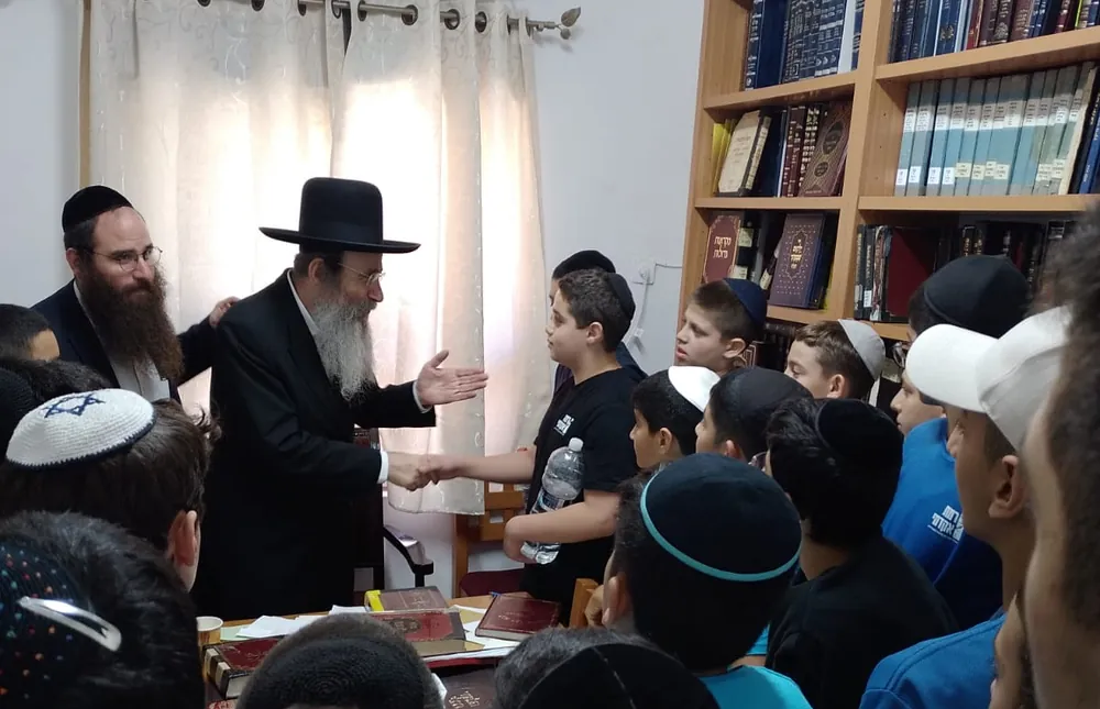 רב לוחץ יד לתלמיד מוקף תלמידים - ימי תשרי בבית המדרש ובכיתות