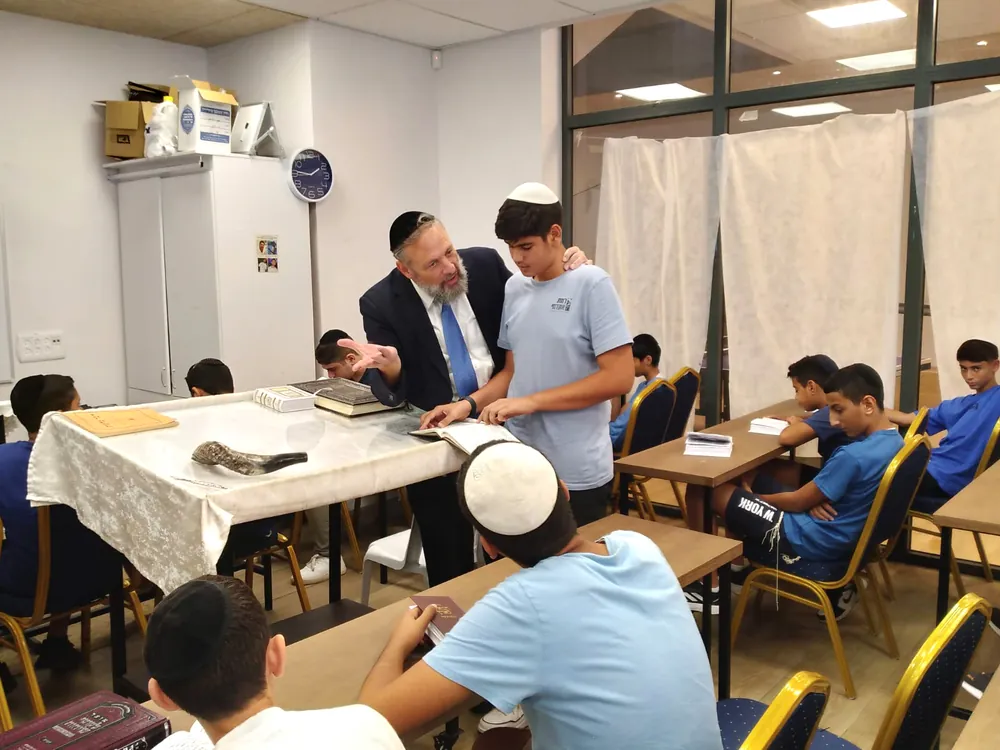 רב מסביר לתלמיד מול ספר פתוח ושופר - ימי תשרי בבית המדרש ובכיתות