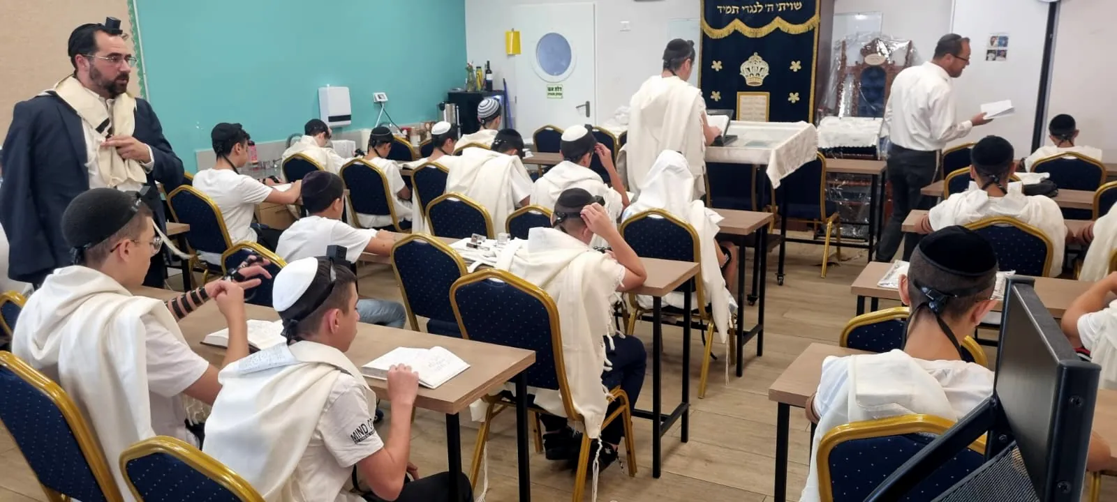 תלמידים מתפללים עם טליתות ותפילין בבית המדרש - ימי תשרי בבית המדרש ובכיתות