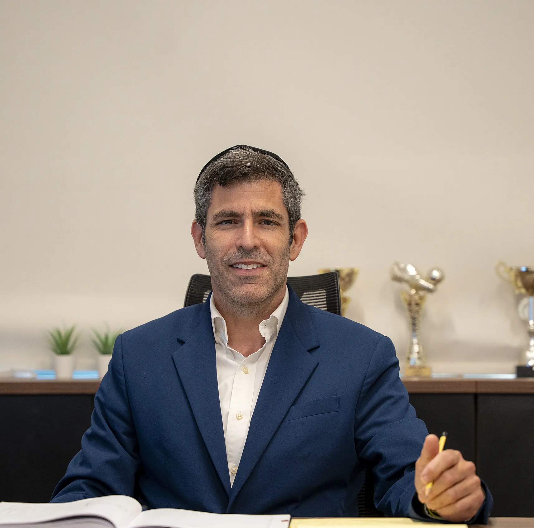 איש צוות יושב ליד שולחן העבודה במשרד ומחייך
