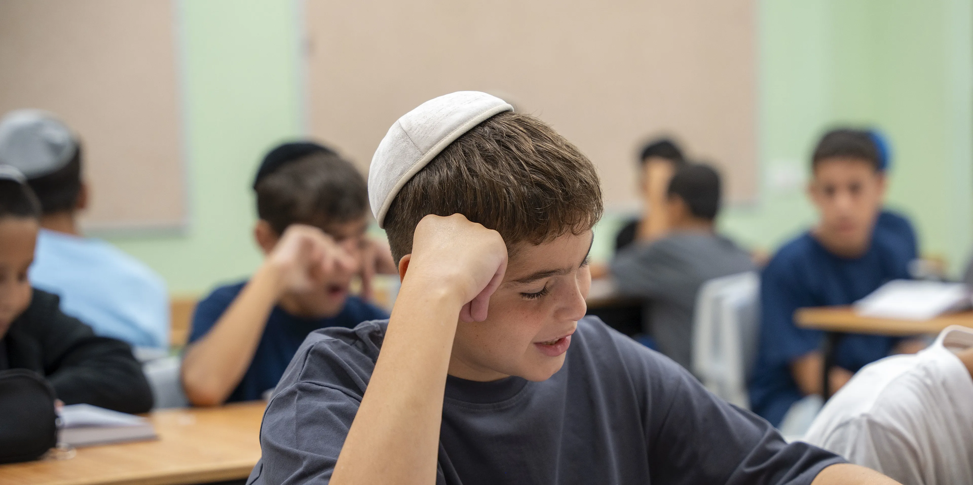 תלמיד מחייך מעל ספר גמרא בכיתה