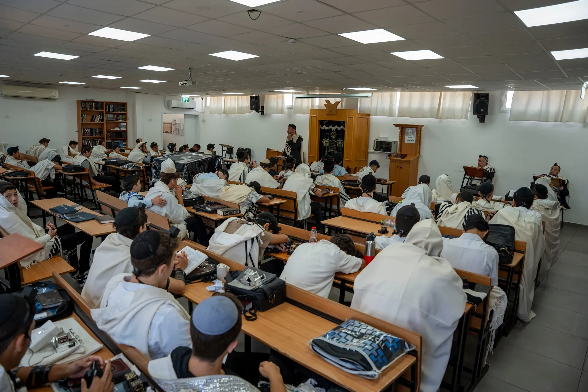 תלמידים עטופים בטלית לומדים באולם בית המדרש