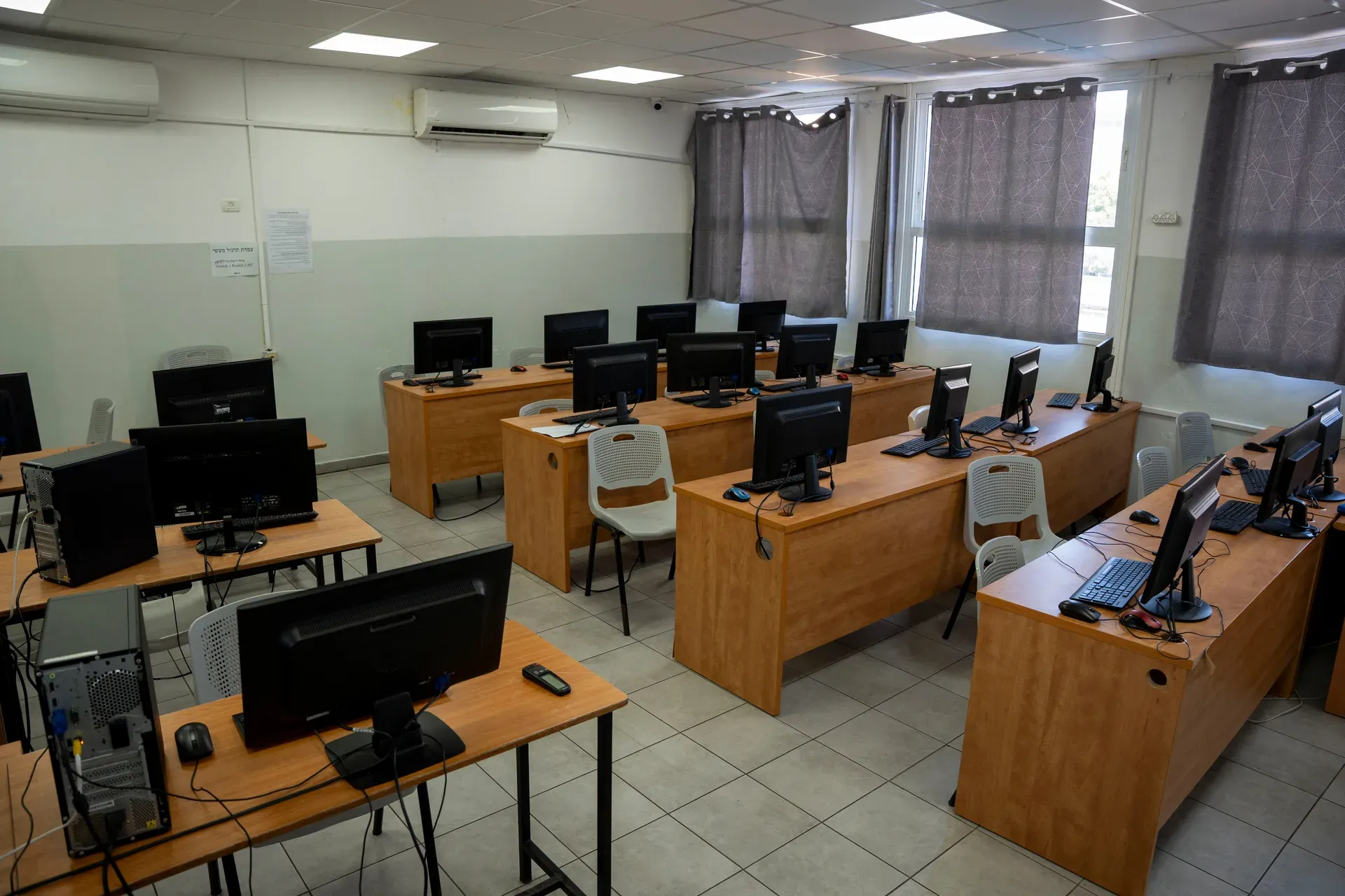 כיתת מחשבים ריקה עם שולחנות ומסכים