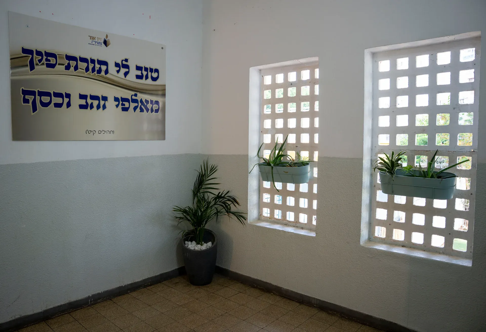 לובי הכניסה עם שלט ברכה, עציצים וחלונות מעוצבים