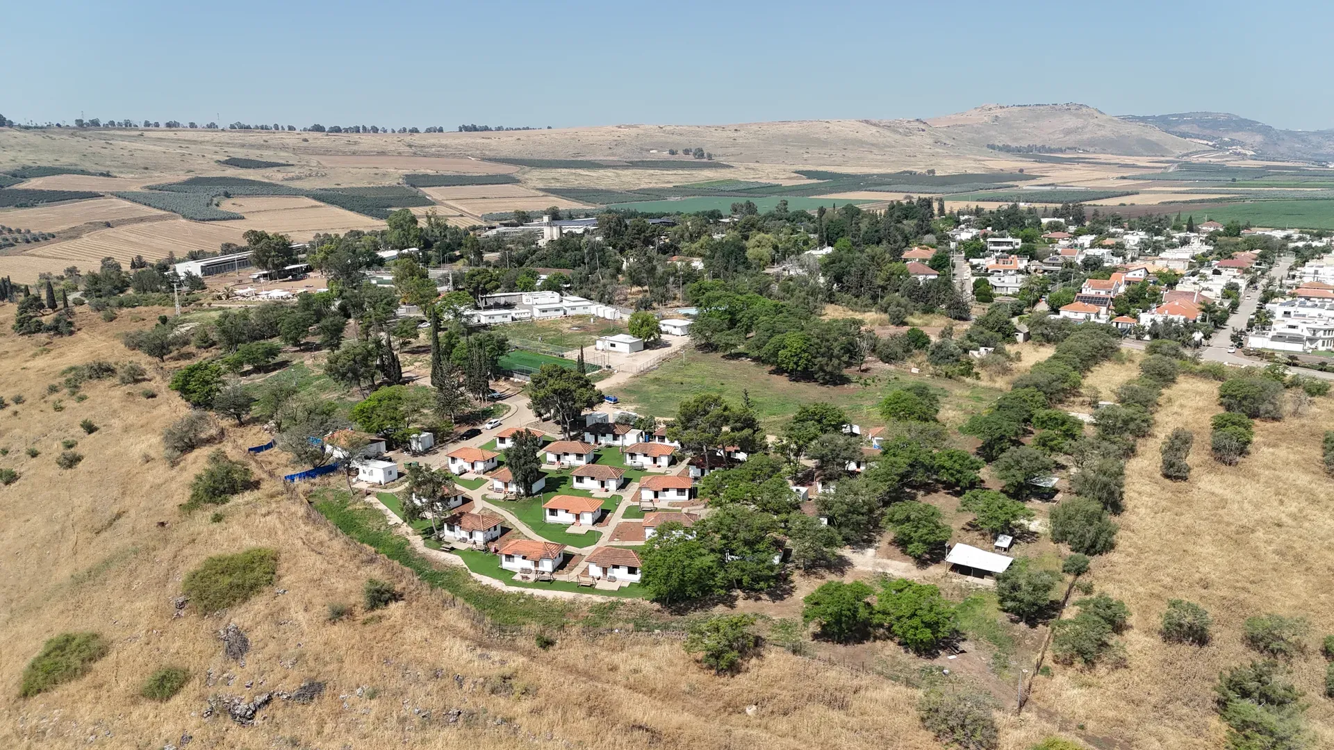 צילום אוויר של יישוב כפרי מוקף שדות, עצים ובתים