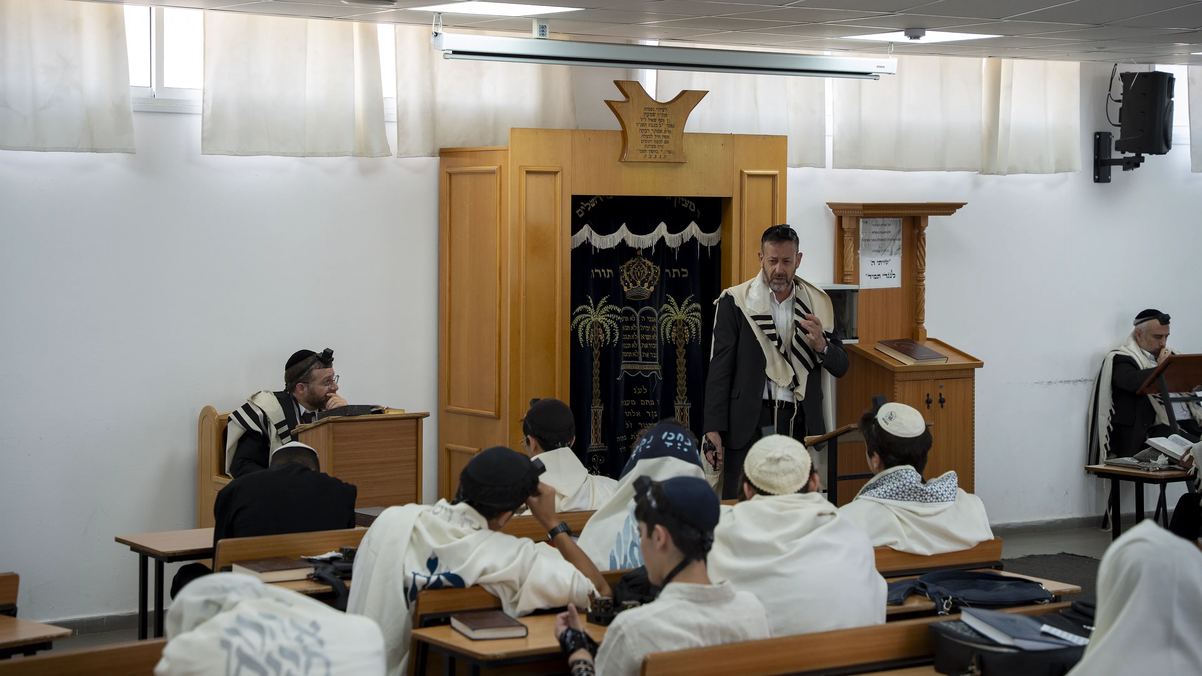 רב בטלית מדבר מול ארון הקודש, תלמידים בבית המדרש