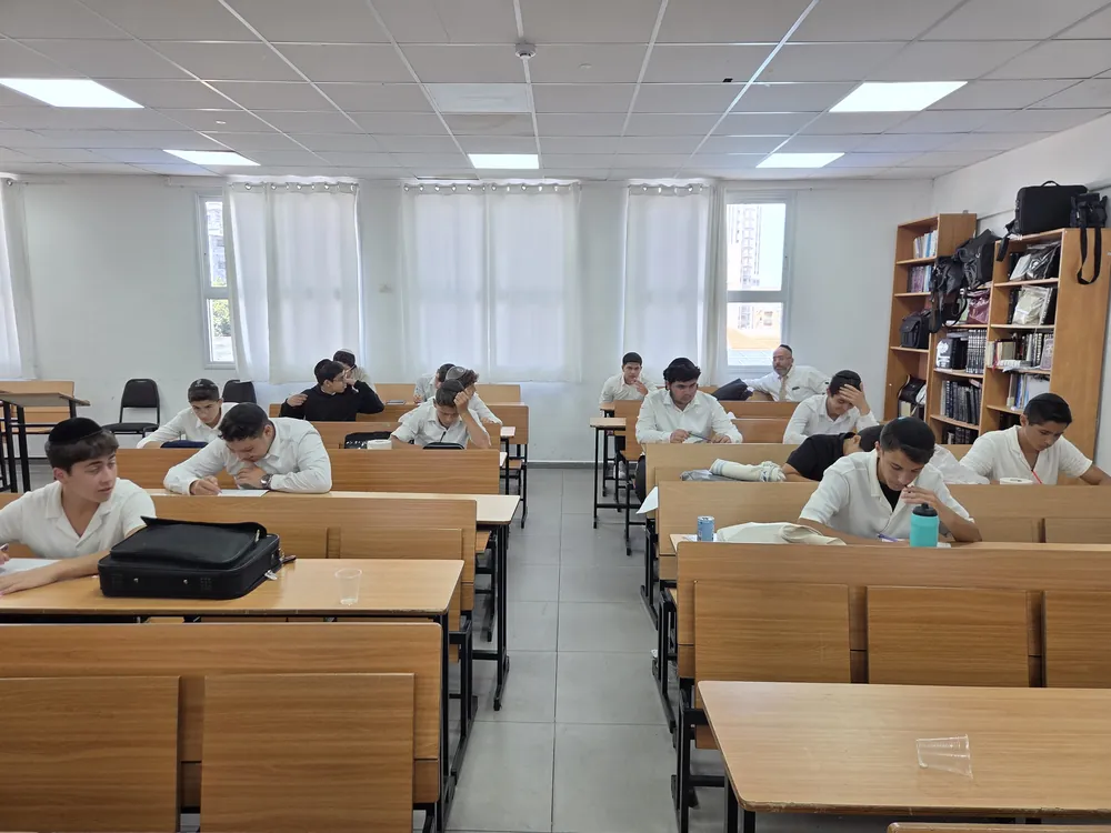 תלמידים כותבים על דפים בשולחנות הכיתה - יום עיון בח׳ בתמוז