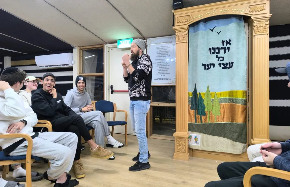 דובר מול תלמידים באולם - בין סלעי המדבר