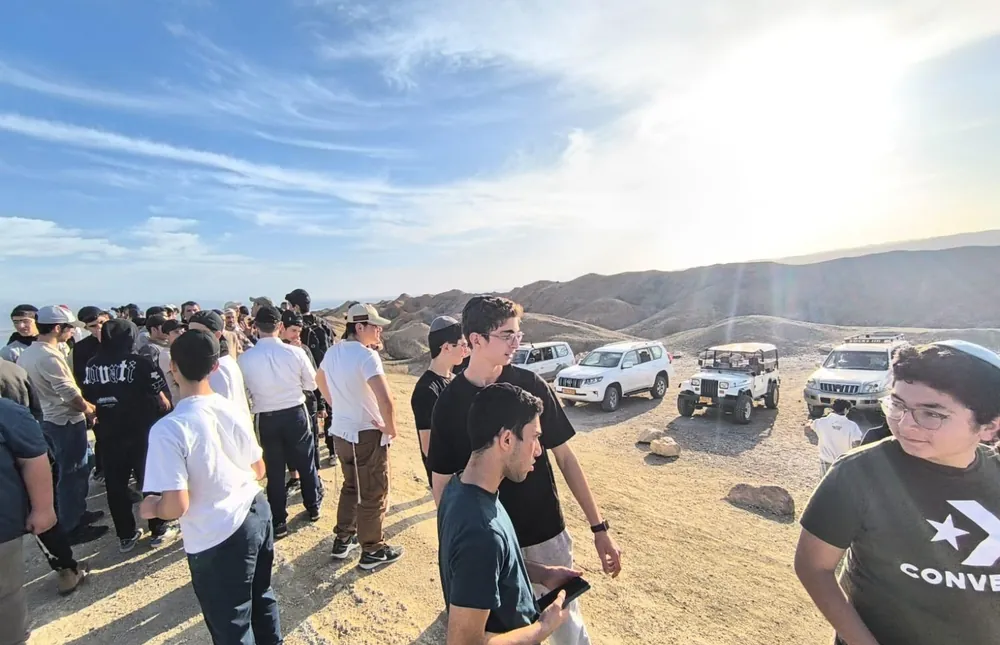 תלמידים ליד רכבי שטח במדבר - בין סלעי המדבר