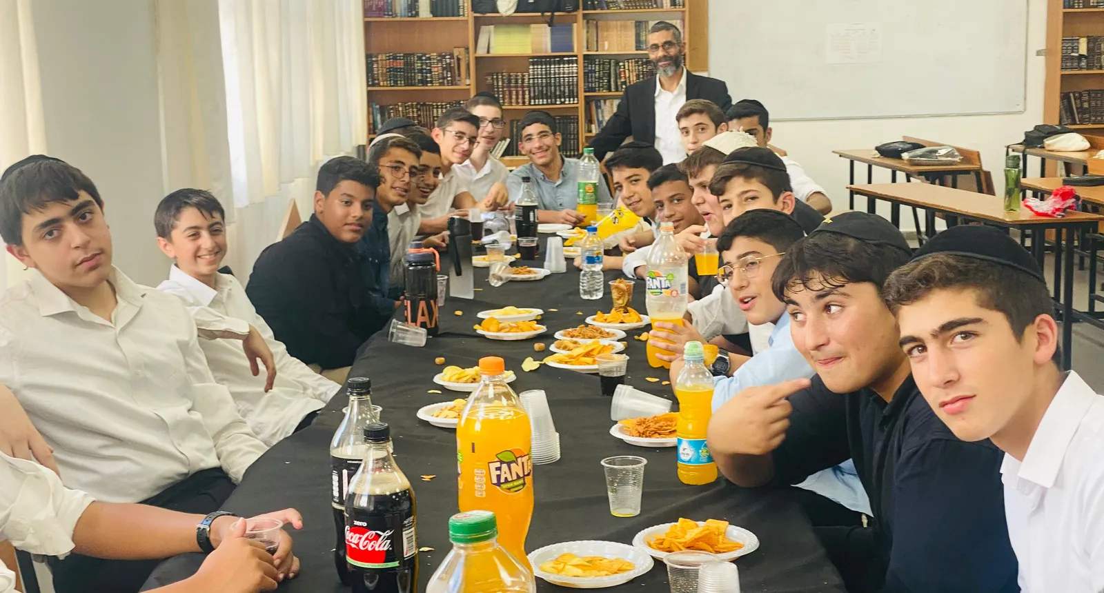 תלמידים מצטלמים סביב שולחן עם חטיפים ושתייה - הזמן הראשון שלהם