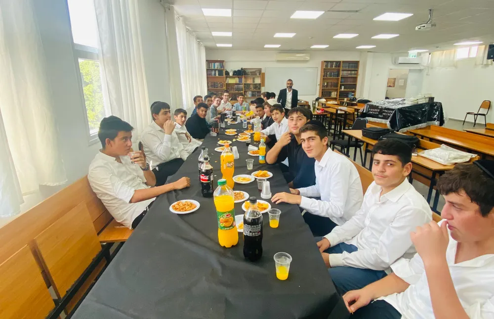 שולחן כיבוד ותלמידים משני צדדיו בכיתה - הזמן הראשון שלהם