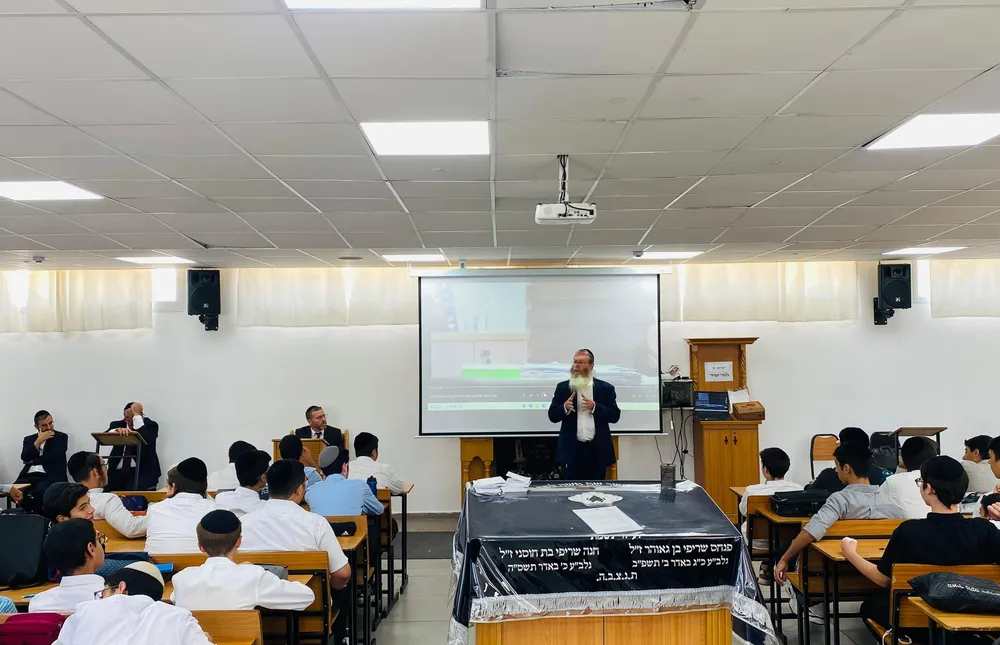 מבט רחב על שיחה לתלמידים באולם עם מסך - קולות מבחוץ