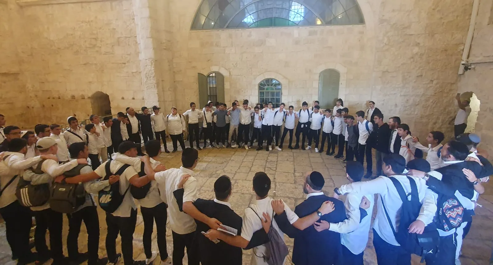 תלמידים עומדים במעגל משולב זרועות באולם אבן - המסע של אלול
