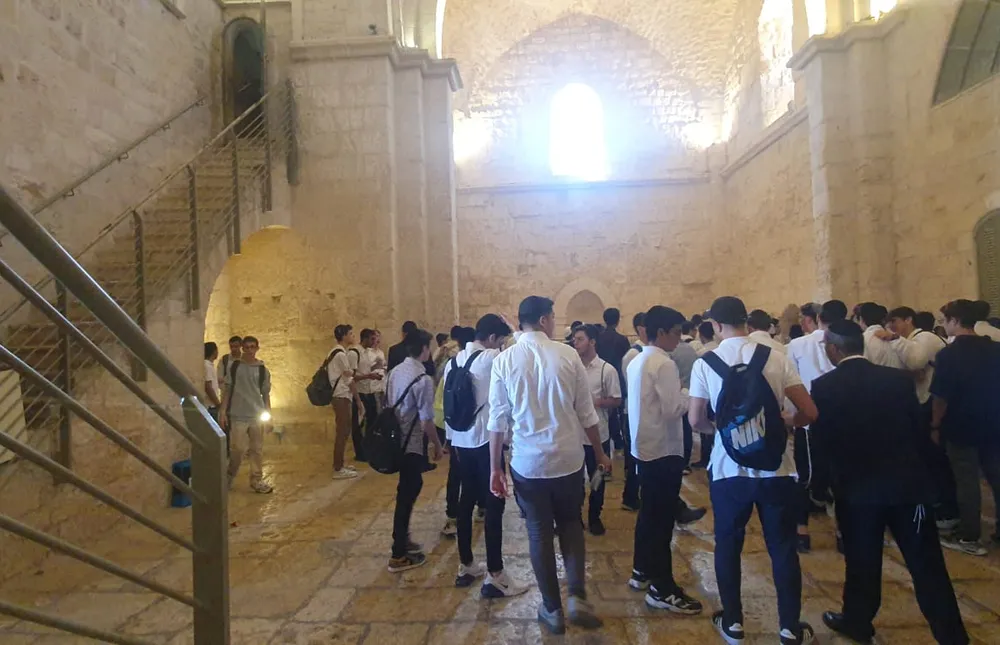 תלמידים מתכנסים באולם אבן עם קשתות - המסע של אלול