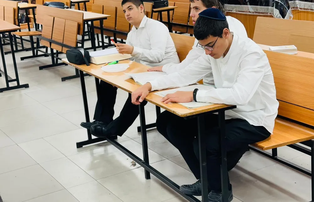 שני תלמידים מעיינים בספרים ליד שולחן - בזוגות מול הספר