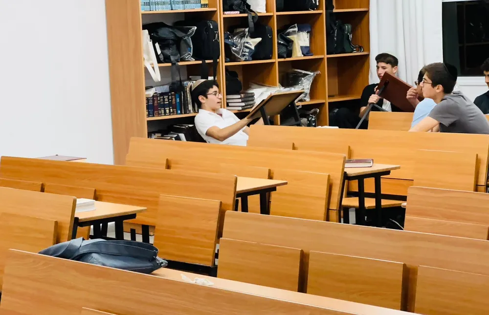 תלמידים יושבים לשיחה ולקריאה ליד ארון הספרים - בזוגות מול הספר