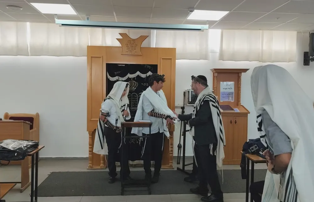 איש בטלית לוחץ יד לתלמיד עטוף בטלית ליד ארון הקודש - הגענו להדרן