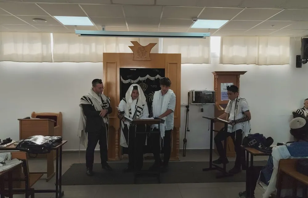 תלמידים בטלית ותפילין קוראים מול ארון הקודש - צילום קבוצתי נוסף - הגענו להדרן