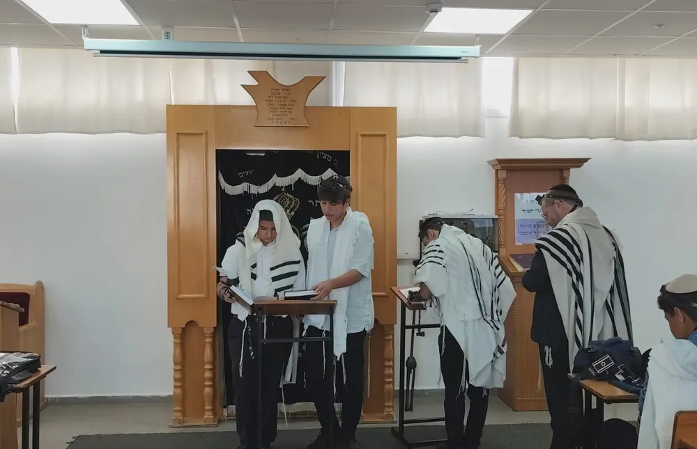 שני תלמידים בטליתות קוראים ספרים מול ארון הקודש - הגענו להדרן
